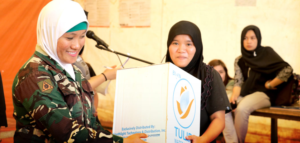 Survivors of the Marawi Siege who are temporarily staying in transitional shelters receive water purifier kits from Fluor Philippines as part of PBSP's efforts to help rehabilitate the city.